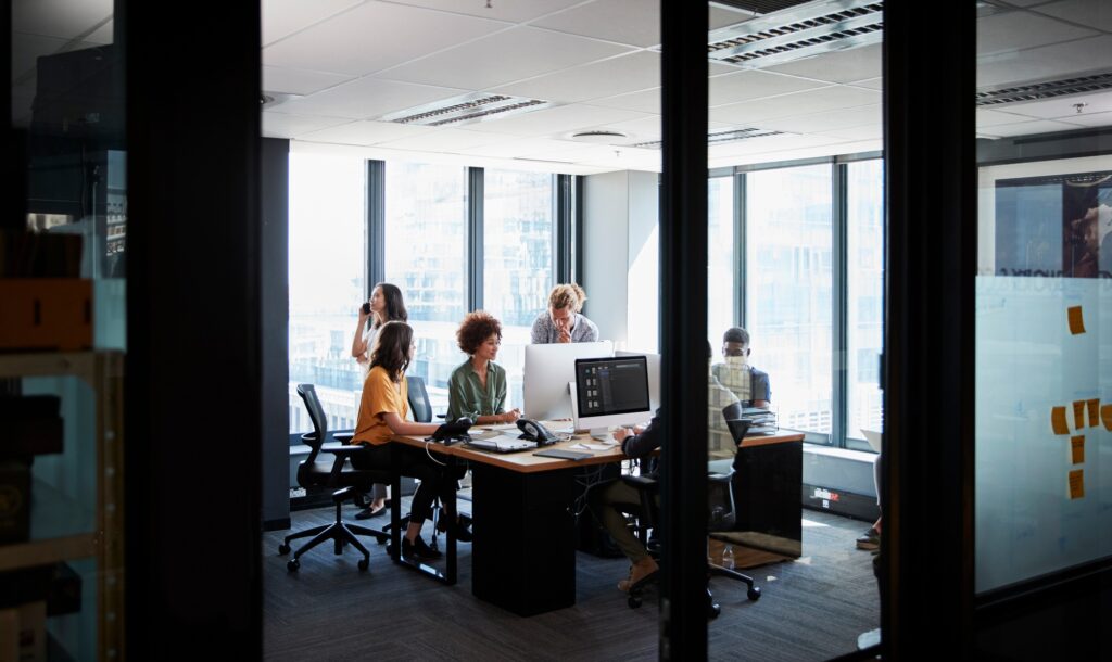 Creative business team working together in a casual office, seen through glass wall